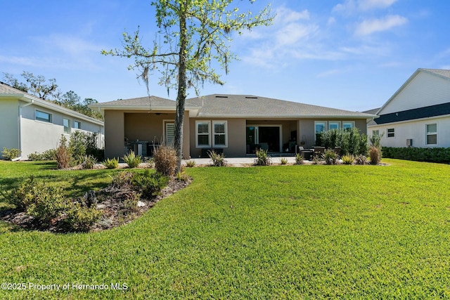 rear view of property featuring stucco siding, a lawn, and a patio