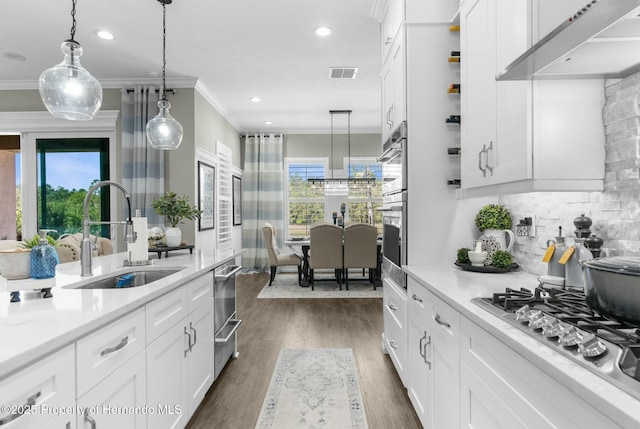 kitchen featuring visible vents, dark wood-style flooring, under cabinet range hood, stainless steel gas cooktop, and a sink