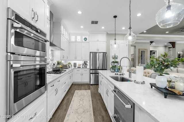 kitchen with stainless steel appliances, a sink, visible vents, white cabinets, and pendant lighting