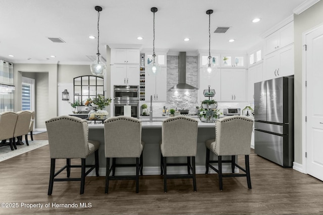 kitchen with stainless steel appliances, wall chimney exhaust hood, visible vents, and crown molding