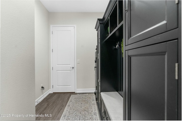 mudroom featuring dark wood-type flooring and baseboards