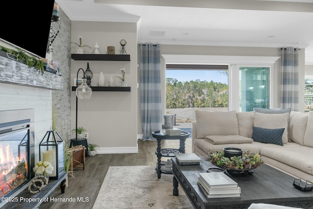 living area featuring a large fireplace, ornamental molding, wood finished floors, and baseboards