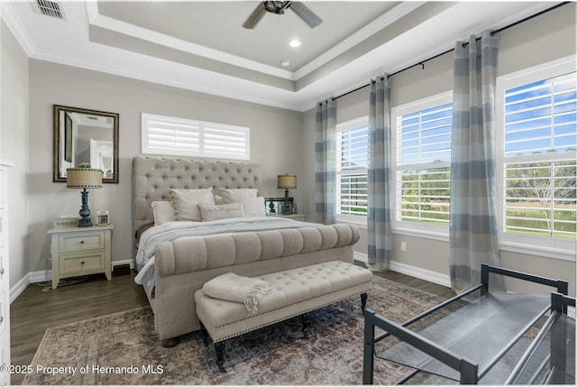 bedroom with ornamental molding, a tray ceiling, visible vents, and wood finished floors