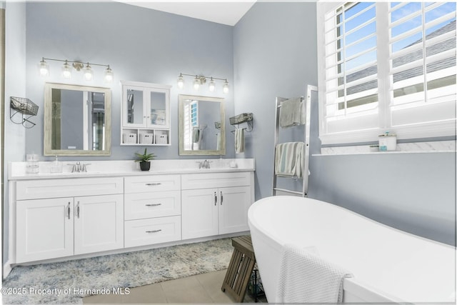 bathroom featuring double vanity, a soaking tub, a sink, and tile patterned flooring