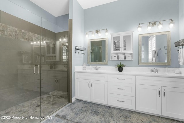 bathroom featuring a stall shower, a sink, and double vanity