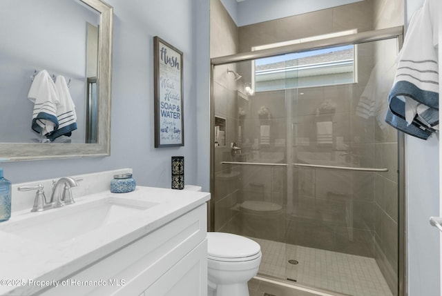 bathroom with a shower stall, toilet, and vanity