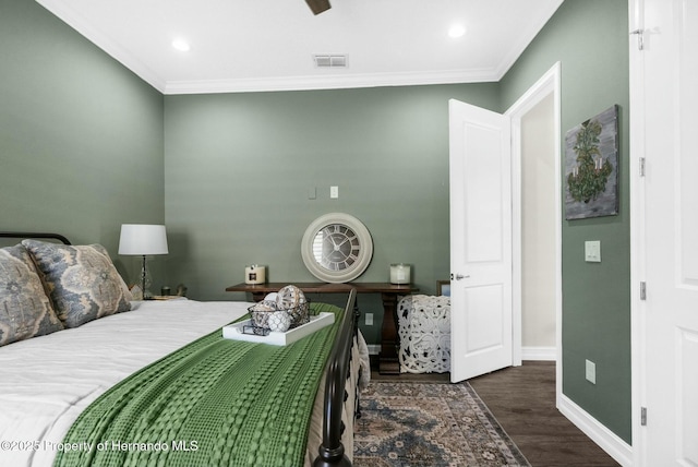 bedroom with baseboards, wood finished floors, visible vents, and crown molding