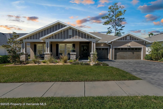 craftsman inspired home featuring decorative driveway, a porch, an attached garage, board and batten siding, and a front lawn