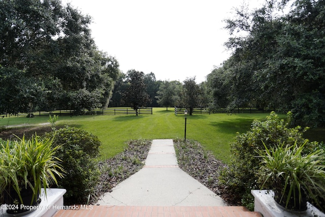 surrounding community featuring a rural view, a yard, and fence