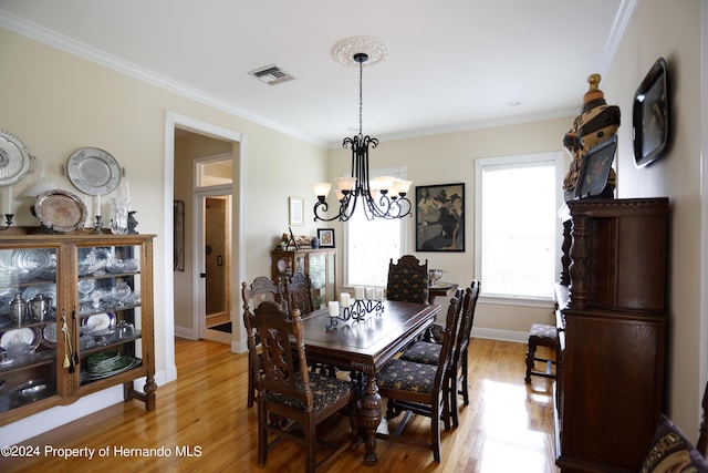 dining room featuring visible vents, a notable chandelier, crown molding, and light wood-style flooring