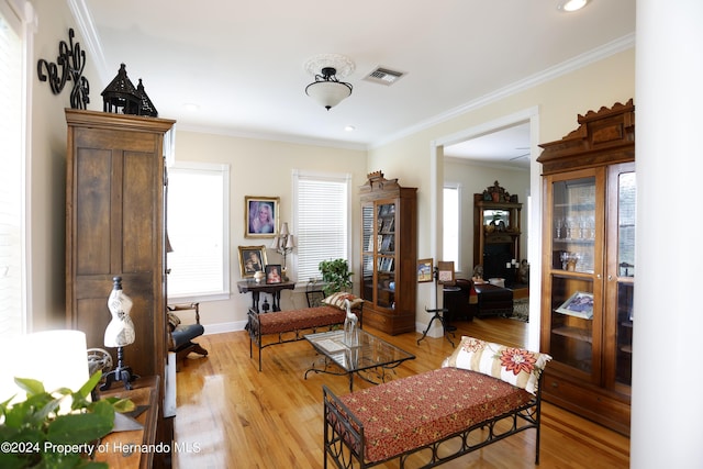 interior space featuring light wood-style floors, a healthy amount of sunlight, ornamental molding, and visible vents