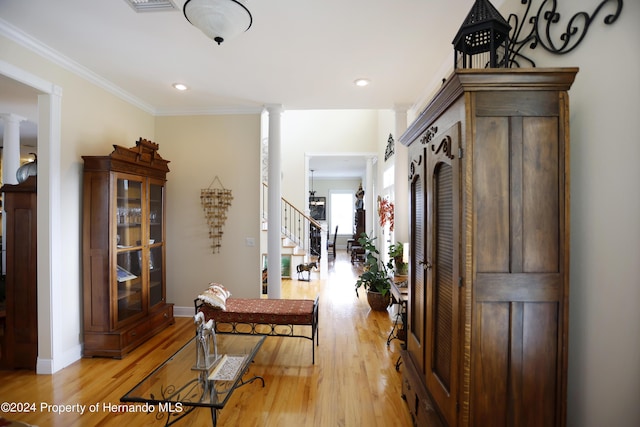 hall with stairway, light wood finished floors, and ornate columns