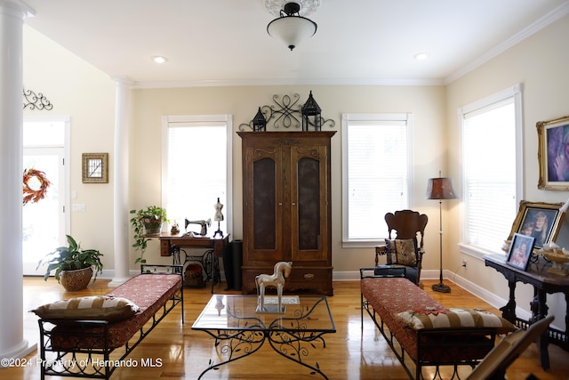 living area with plenty of natural light, decorative columns, baseboards, and light wood finished floors