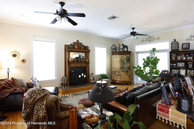 living room featuring ornamental molding, visible vents, plenty of natural light, and a fireplace with raised hearth