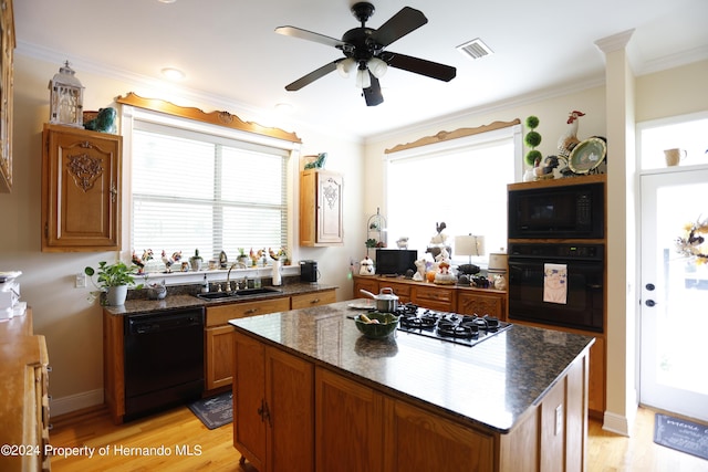 kitchen featuring visible vents, a sink, light wood finished floors, and black appliances