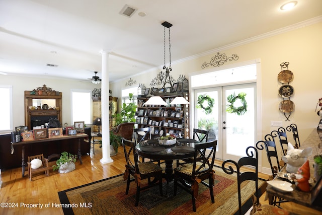 dining area with a healthy amount of sunlight, decorative columns, crown molding, and wood finished floors