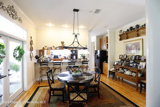 dining area featuring a healthy amount of sunlight, light wood-style floors, and crown molding