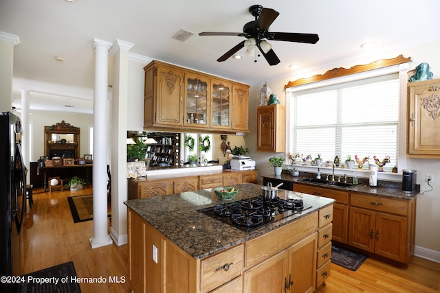 kitchen with visible vents, light wood-style floors, a sink, black appliances, and ornate columns