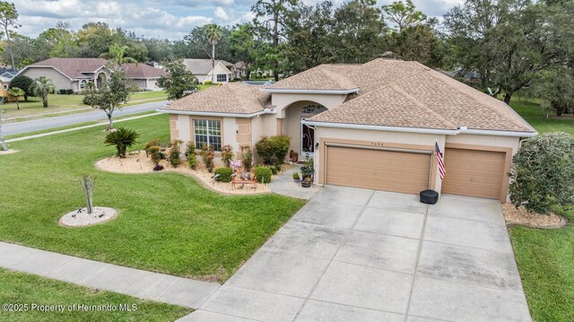 single story home with an attached garage, driveway, a front yard, and stucco siding