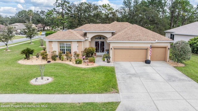 view of front of property featuring a garage, driveway, roof with shingles, stucco siding, and a front yard