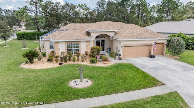 view of front facade featuring stucco siding, a shingled roof, a front yard, a garage, and driveway