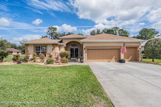 mediterranean / spanish home with a garage, driveway, a front yard, and stucco siding