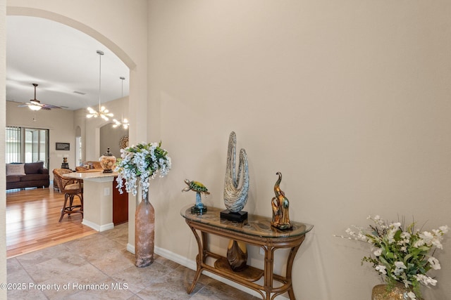 interior space with arched walkways, light tile patterned floors, a chandelier, and baseboards