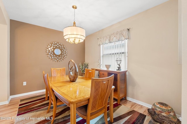 dining room with baseboards, light wood finished floors, and a notable chandelier