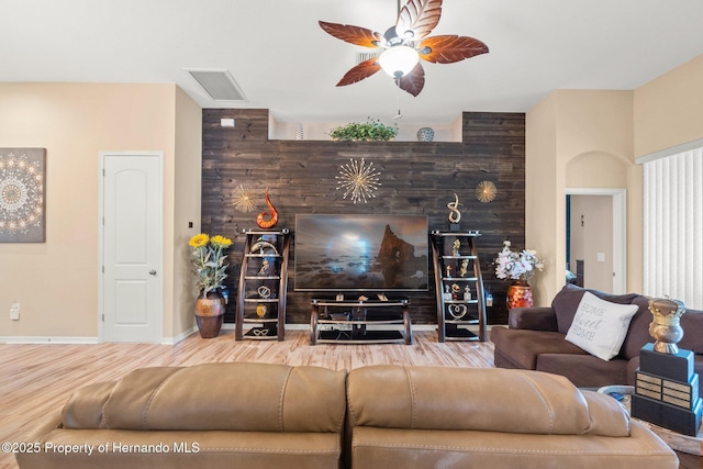 living area featuring baseboards, wood finished floors, visible vents, and a ceiling fan