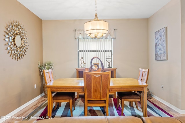 dining space featuring baseboards, a chandelier, and wood finished floors