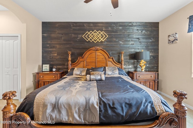 carpeted bedroom with wooden walls, an accent wall, and arched walkways