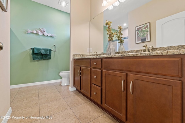 bathroom featuring double vanity, toilet, a sink, baseboards, and tile patterned floors