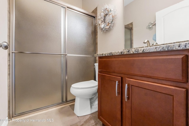 bathroom featuring a shower stall, toilet, and vanity