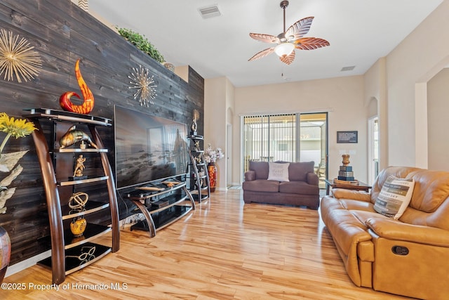 living area featuring visible vents, arched walkways, ceiling fan, and wood finished floors