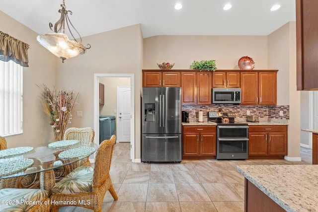 kitchen featuring stainless steel appliances, vaulted ceiling, backsplash, brown cabinets, and light stone countertops