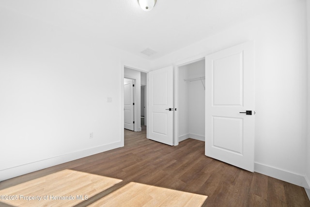 unfurnished bedroom with visible vents, a closet, baseboards, and wood finished floors