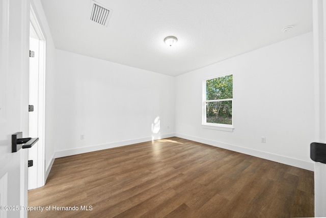 unfurnished room featuring baseboards, visible vents, and wood finished floors