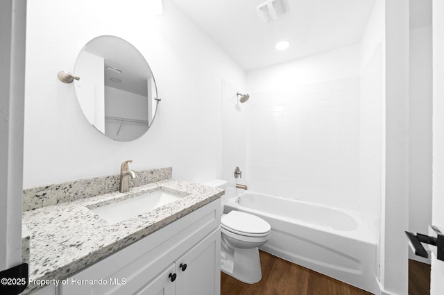 bathroom featuring visible vents, toilet, wood finished floors, bathtub / shower combination, and vanity