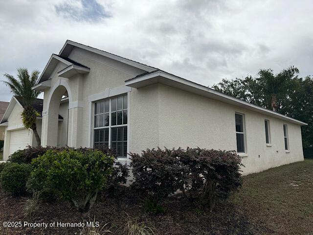 5165 Greystone Dr, Spring Hill, FL 34609 - view of home's exterior with an attached garage and stucco siding