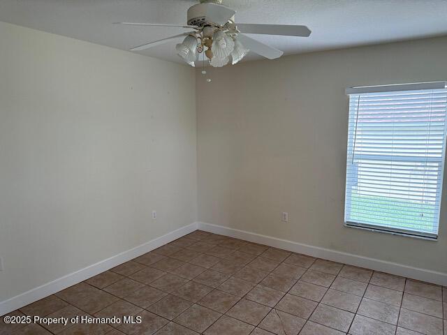 5165 Greystone Dr, Spring Hill, FL 34609 - unfurnished room with light tile patterned flooring, a healthy amount of sunlight, ceiling fan, and baseboards