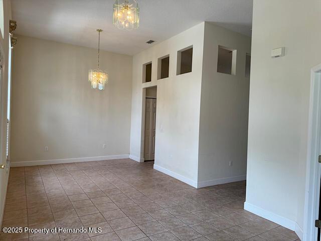 5165 Greystone Dr, Spring Hill, FL 34609 - tiled spare room with visible vents, baseboards, and a chandelier