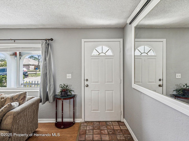 entryway with a textured ceiling, baseboards, and wood finished floors