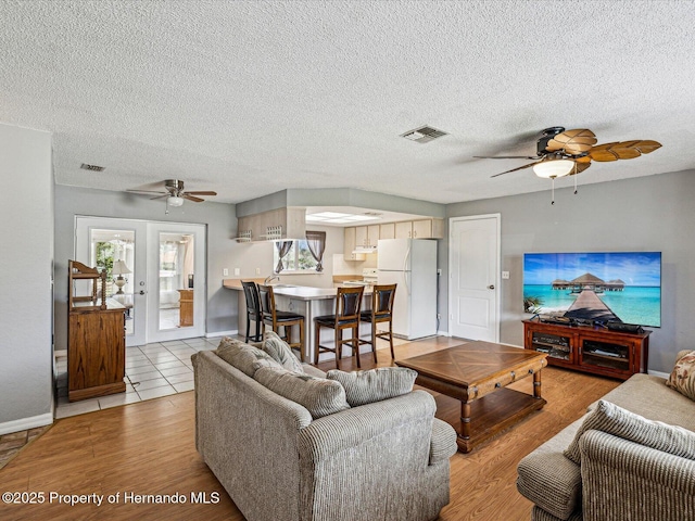 living room with light wood-style floors, ceiling fan, and visible vents