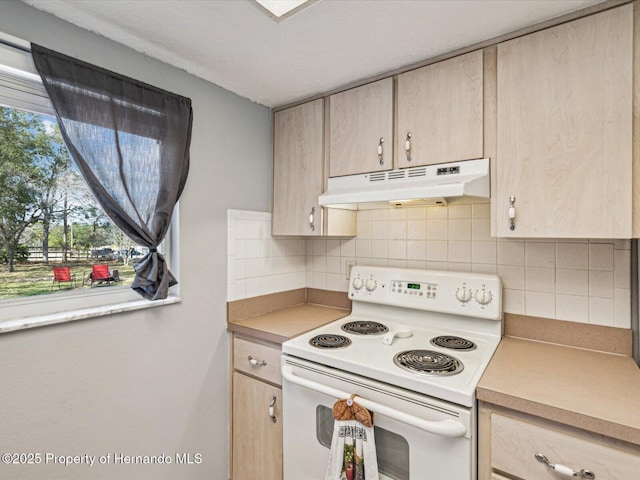 kitchen featuring white electric range oven, tasteful backsplash, light countertops, light brown cabinetry, and under cabinet range hood