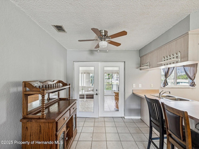 kitchen featuring french doors, open shelves, visible vents, a healthy amount of sunlight, and a sink