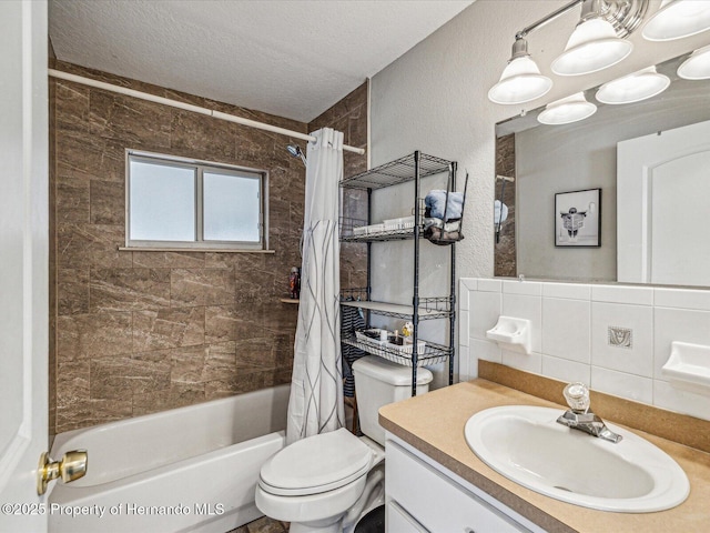 bathroom featuring toilet, shower / bathtub combination with curtain, a textured ceiling, vanity, and tile walls