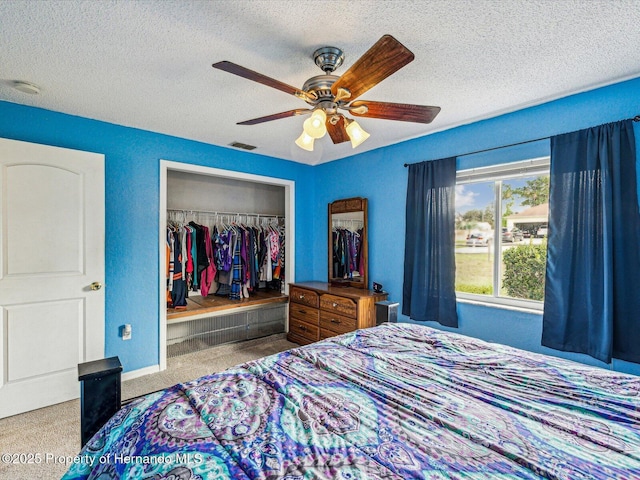 bedroom featuring ceiling fan, a textured ceiling, visible vents, and a closet