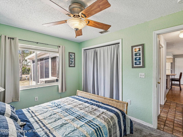 bedroom featuring baseboards, visible vents, a textured wall, ceiling fan, and a textured ceiling