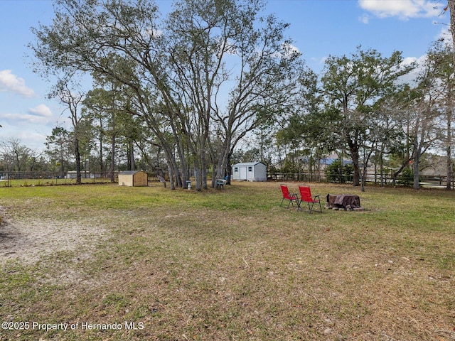 view of yard featuring an outbuilding, fence, and a storage shed