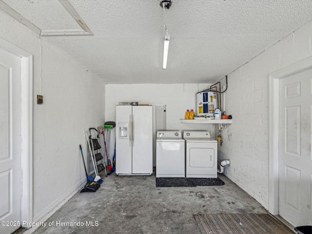 laundry room featuring concrete block wall, electric water heater, a textured ceiling, and separate washer and dryer